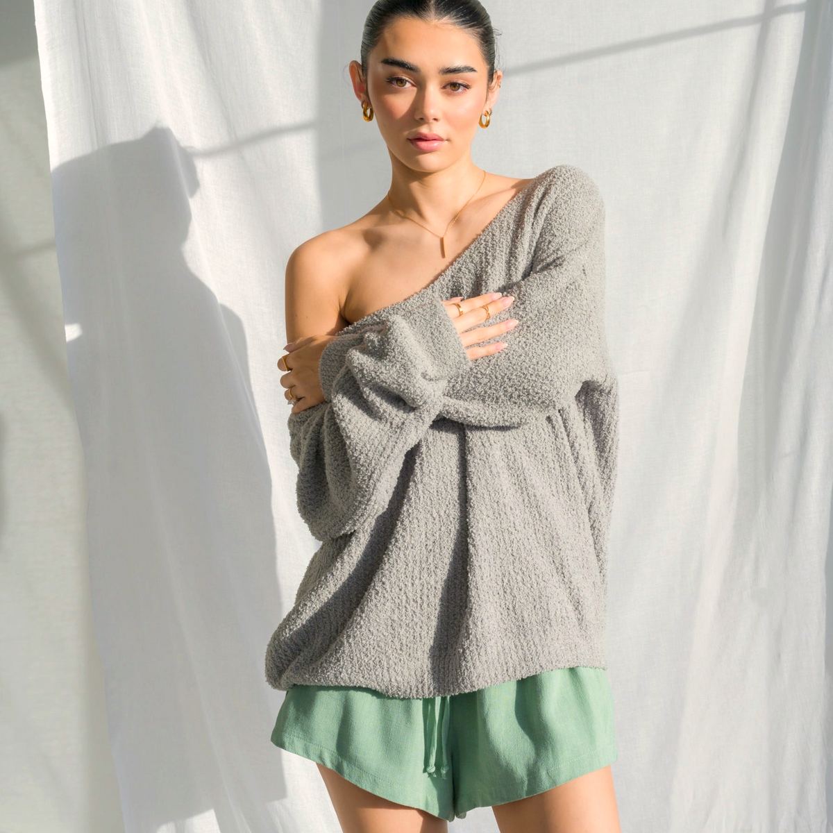 Model wearing an OKAKIE oversized charcoal grey fuzzy teddy bear sweater with a V-neck and drop shoulder sleeves.
