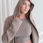 OKAKIE Adrienne heavyweight hooded cardigan in a soft taupe knit with an oversized hood worn by a woman