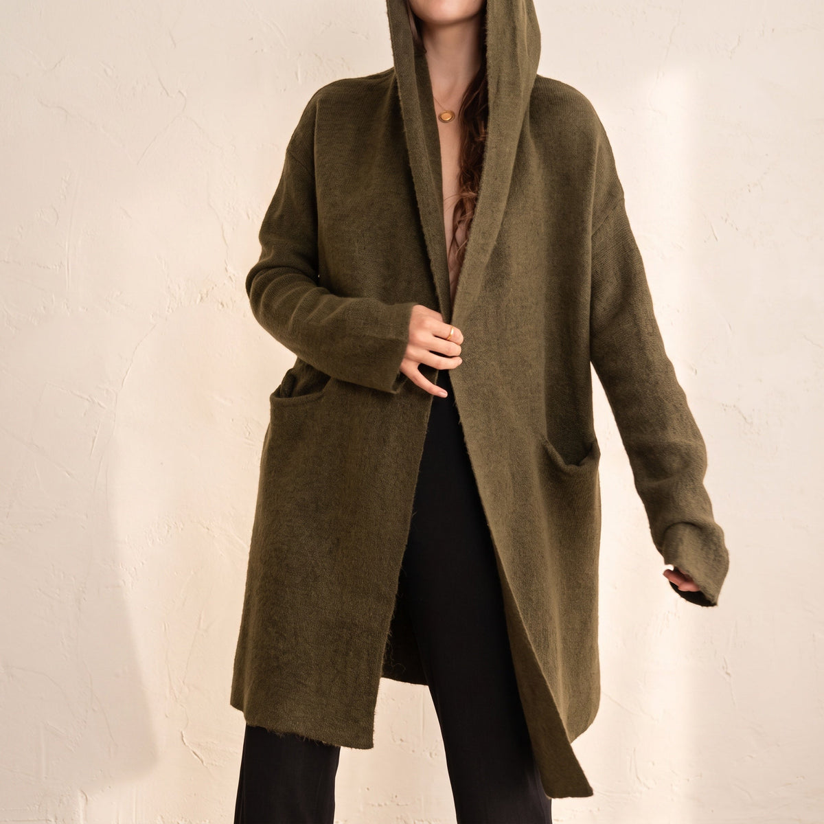 OKAKIE Adrienne heavyweight olive green hooded cardigan with an open front, long sleeves, and deep patch pockets.