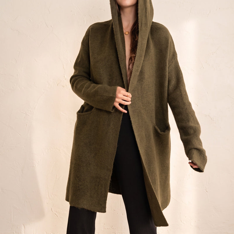 OKAKIE Adrienne heavyweight olive green hooded cardigan with an open front, long sleeves, and deep patch pockets.