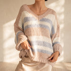 OKAKIE Amélie plush oversized V-neck sweater in pastel taupe, ivory, and pale blue stripes with dropped shoulders.