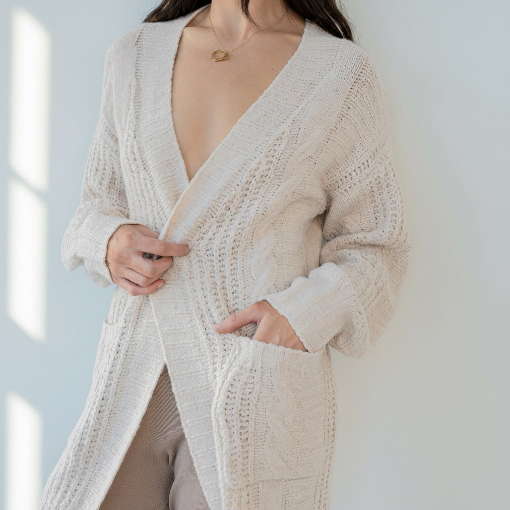 OKAKIE beige cable knit cardigan with oversized patch pockets, drop shoulders, and a collarless design on a model.