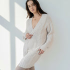 OKAKIE beige cable knit cardigan with a collarless design, drop shoulders, and patch pockets on a model