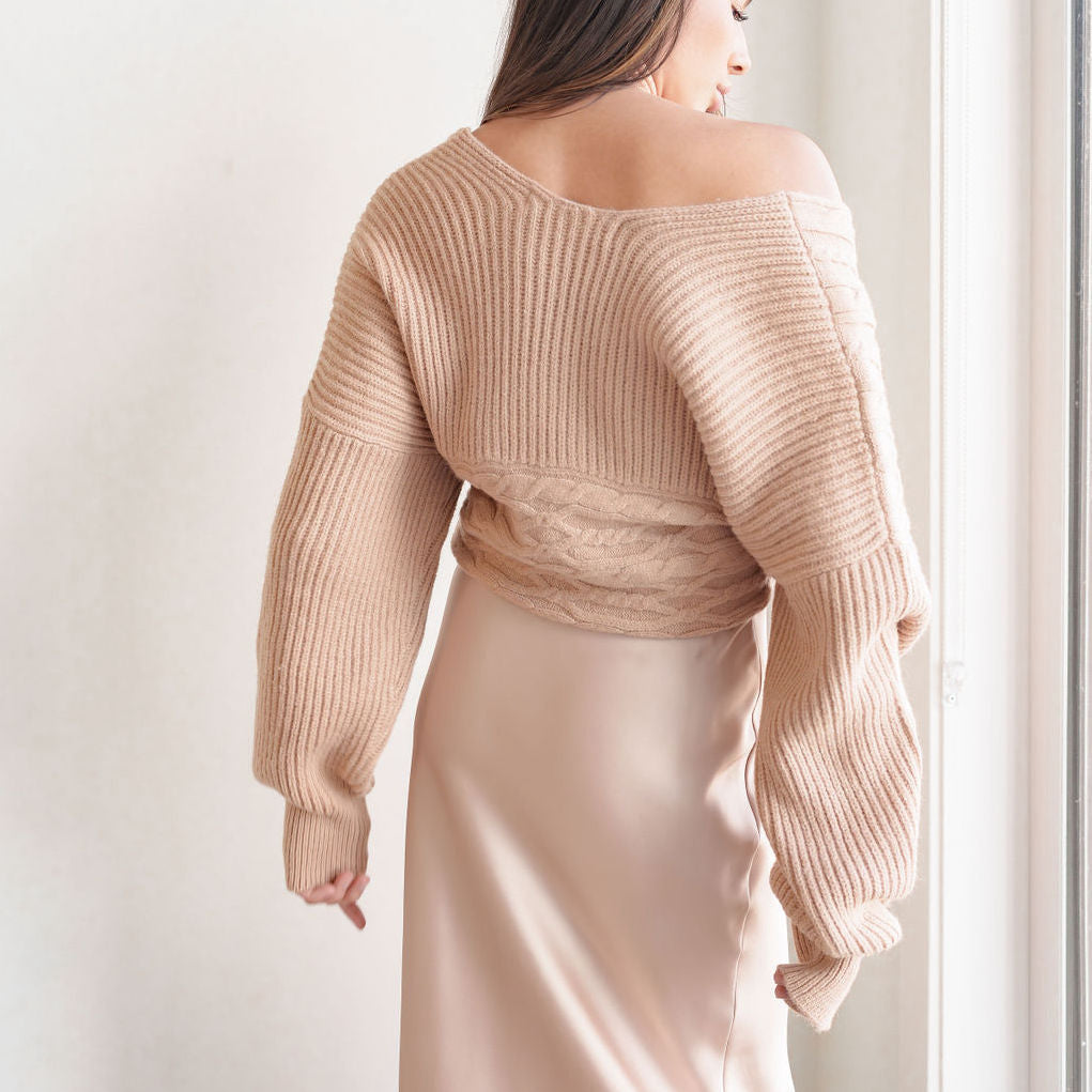 OKAKIE Amélie crossover cable knit sweater in beige with voluminous sleeves and ribbed detailing, back view.