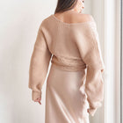 OKAKIE Amélie crossover cable knit sweater in beige with voluminous sleeves and ribbed detailing, back view.