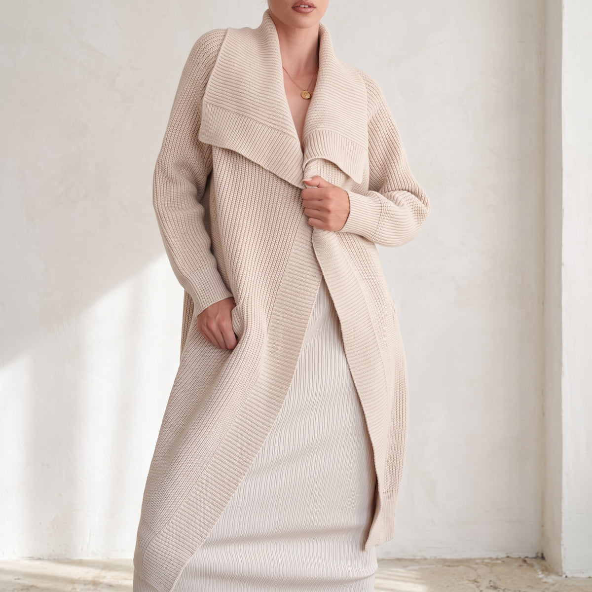 OKAKIE beige heavy knit coatigan with oversized lapel, drop shoulders, and patch pockets worn over a matching dress.