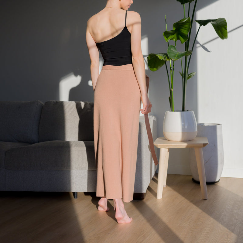 OKAKIE beige midi wrap knit skirt with adjustable waist tie worn by a woman in a sunlit room
