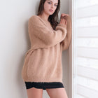 OKAKIE model wearing a beige oversized mohair-feel tunic sweater with dropped shoulders and a soft boat neckline.