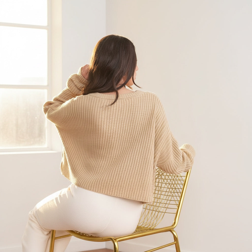 Back view of a woman wearing an OKAKIE beige oversized purl knit cropped sweater with drop shoulders.