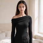 Model wearing OKAKIE black asymmetric draped sweater top with long sleeves and fine ribbed knit texture