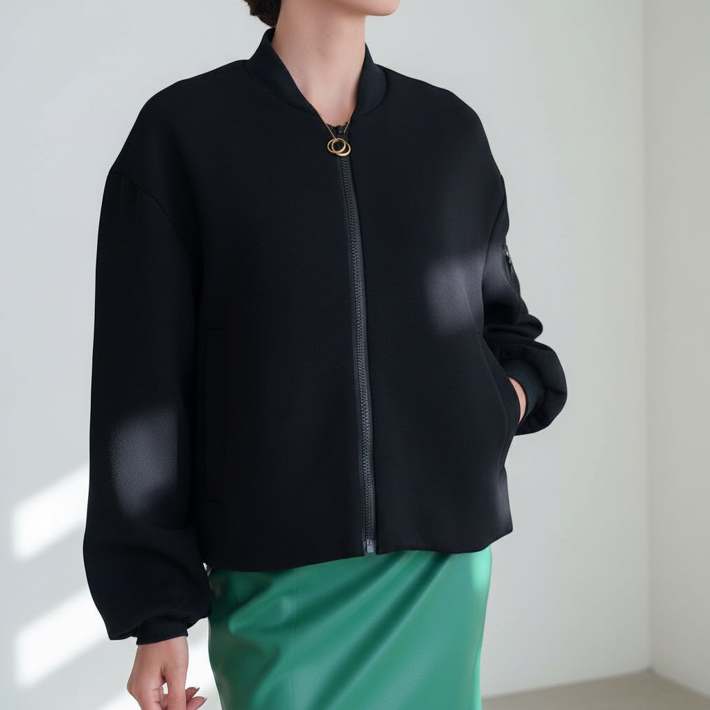 OKAKIE black bomber jacket with a front zipper closure and ribbed cuffs worn over a green skirt