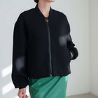 OKAKIE black bomber jacket with a front zipper closure and ribbed cuffs worn over a green skirt