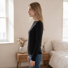 Model wearing a black OKAKIE long-sleeve boat neck top in a soft brushed knit with a relaxed fit and straight hem.