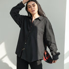 Model wearing an OKAKIE black cotton reversible shacket with Southwestern-inspired patterned lining and snap buttons.