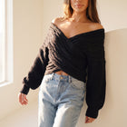 OKAKIE black cable knit sweater with a criss cross off-shoulder design and wide dolman sleeves on a model