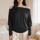 OKAKIE Maëlle black hacci knit top with a wide boat neckline worn off-shoulder, featuring relaxed dolman sleeves.