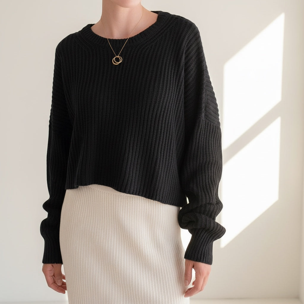 OKAKIE black oversized purl knit cropped sweater with crew neckline and drop shoulder sleeves worn with a white skirt