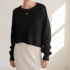 OKAKIE black oversized purl knit cropped sweater with crew neckline and drop shoulder sleeves worn with a white skirt