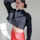 Model wearing an OKAKIE black ribbed crop sweater with a high neckline and long sleeves, featuring a lustrous finish.