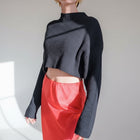 OKAKIE black ribbed crop sweater with a high neckline and long sleeves worn with a red satin skirt