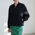 OKAKIE black structured bomber jacket with a collarless neckline, front zipper, and voluminous sleeves.