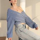 OKAKIE blue cable knit sweater with a criss cross adjustable v-neckline and wide dolman sleeves worn off-shoulder