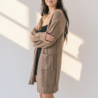 OKAKIE brown cable knit cardigan with oversized patch pockets and drop shoulders worn by a model in a loose fit