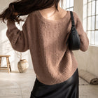 OKAKIE brown fuzzy ribbed knit sweater with a relaxed fit and V-neckline worn by a model with a black shoulder bag.