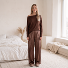 OKAKIE Maëlle draped brown hacci knit top with a wide boat neckline worn off-shoulder, styled with satin trousers.