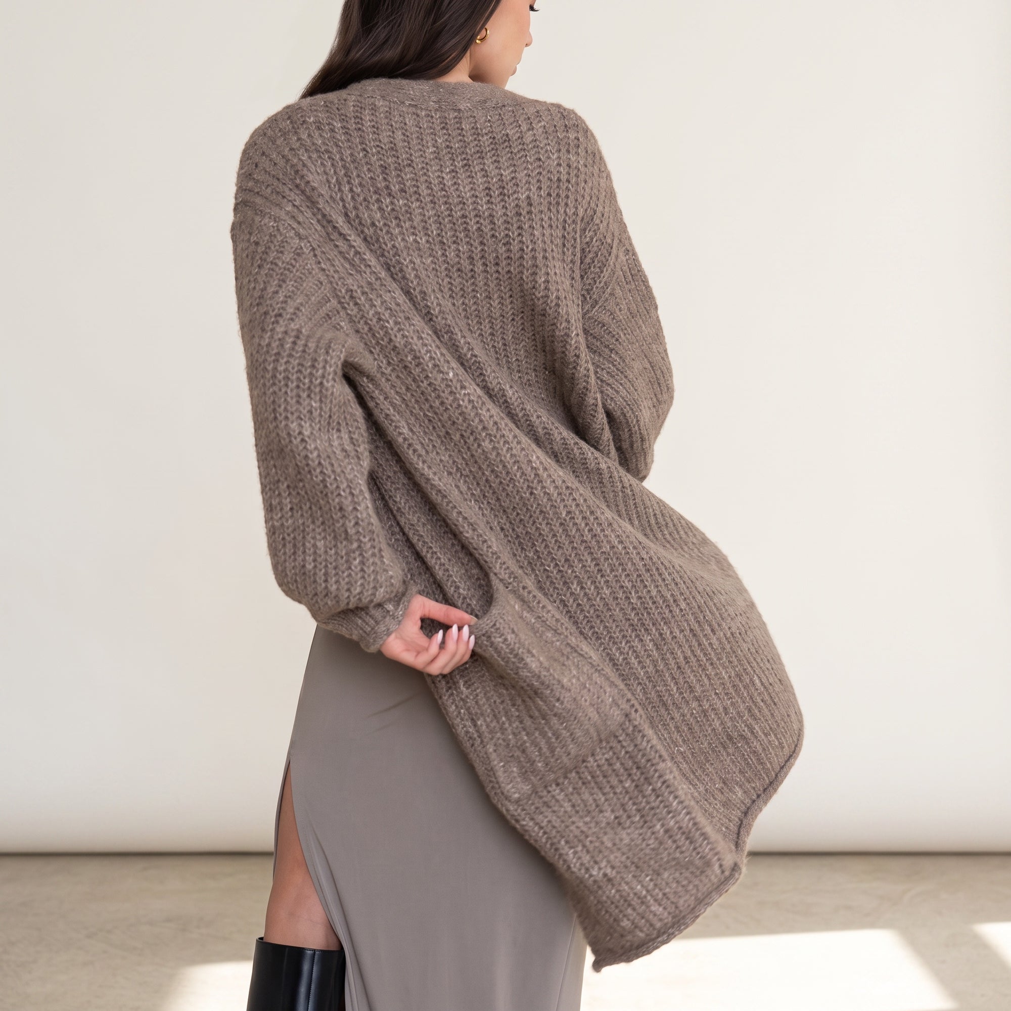 OKAKIE heavy warm brown purl knit cardigan worn over a grey dress, back view showing textured chunky knit fabric.