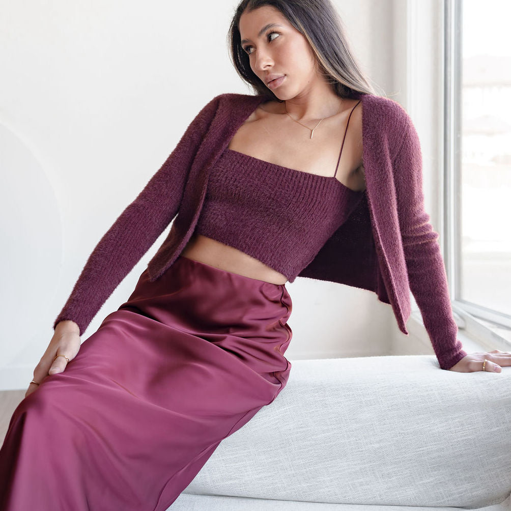 Model wearing OKAKIE burgundy fuzzy knit tank and matching bolero cardigan with a satin midi skirt