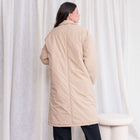 Back view of a model wearing the OKAKIE Camille padded beige trench coat with a longline silhouette and relaxed fit.