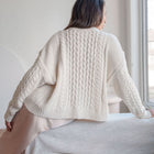 OKAKIE cream oversized cable knit cotton sweater with dropped shoulders and ribbed hem worn by a woman