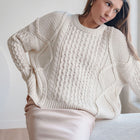 OKAKIE cream oversized cable knit sweater with mixed textures and crew neck worn by a woman