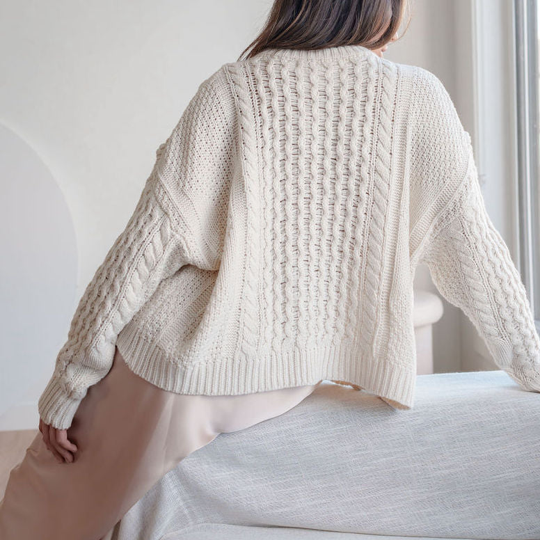 OKAKIE cream oversized cable knit cotton sweater with dropped shoulders and ribbed hem, viewed from the back.