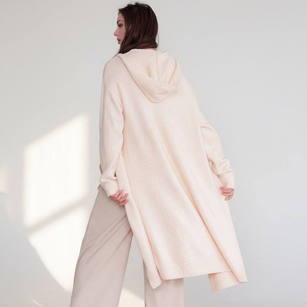 OKAKIE cream hooded maxi cardigan in a thick purl knit texture with oversized pockets, worn by a model from behind.