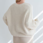 Back view of an OKAKIE cream-colored mohair tunic sweater with a relaxed fit, dropped shoulders, and fuzzy texture.