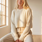 OKAKIE cream oversized purl knit cropped sweater with a crew neckline and drop shoulders worn by a blonde model