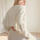 OKAKIE cream oversized purl knit cropped sweater with drop shoulders and crew neckline worn by a blonde model