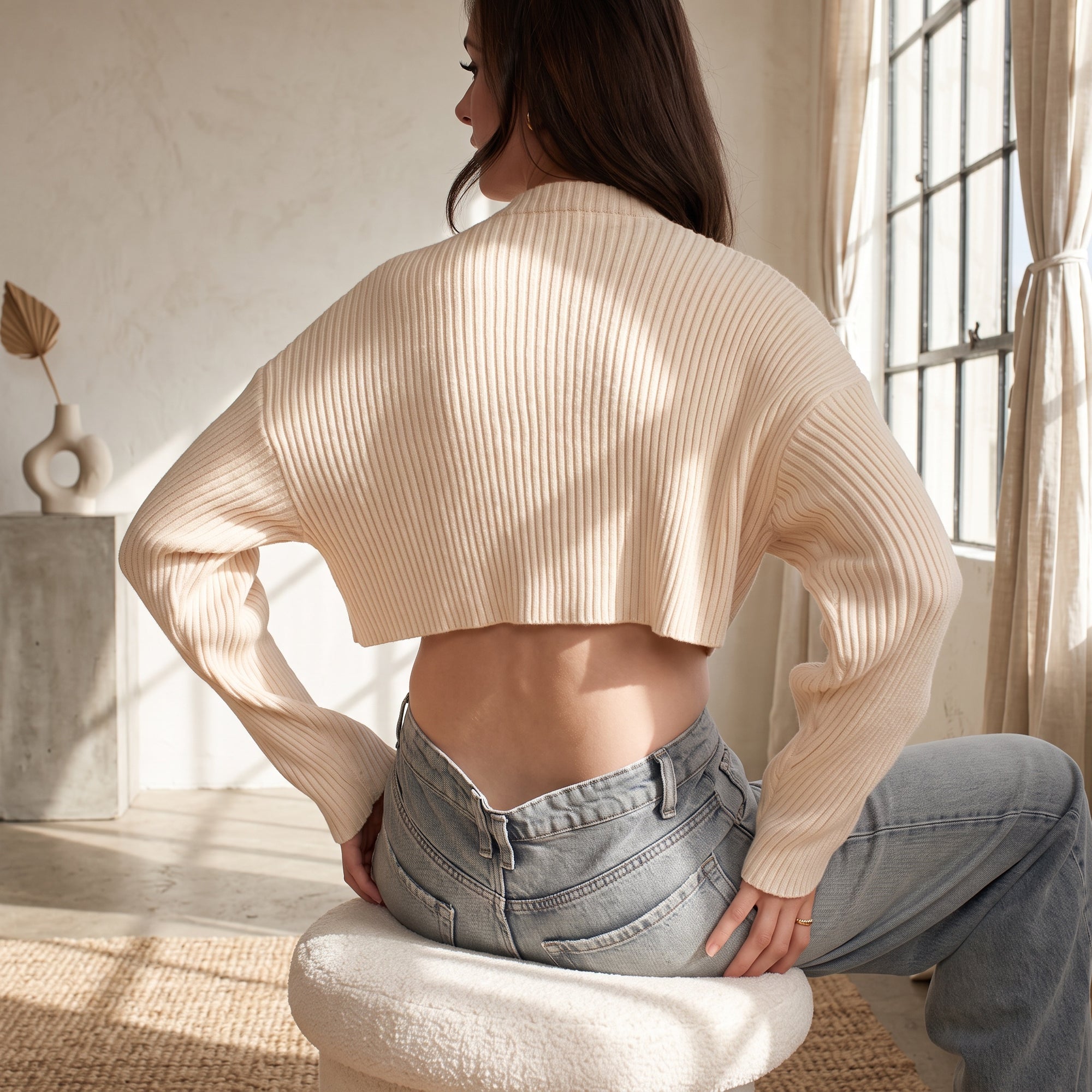 OKAKIE cream ribbed crop sweater with high neckline and long sleeves worn by a model in a sunlit room