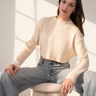 OKAKIE model wearing a cream-colored cropped ribbed sweater with a high neckline and long sleeves, paired with jeans.