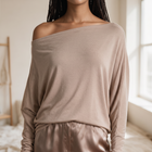 OKAKIE Maëlle draped hacci knit top in beige with a wide boat neckline worn off-shoulder and relaxed dolman sleeves.