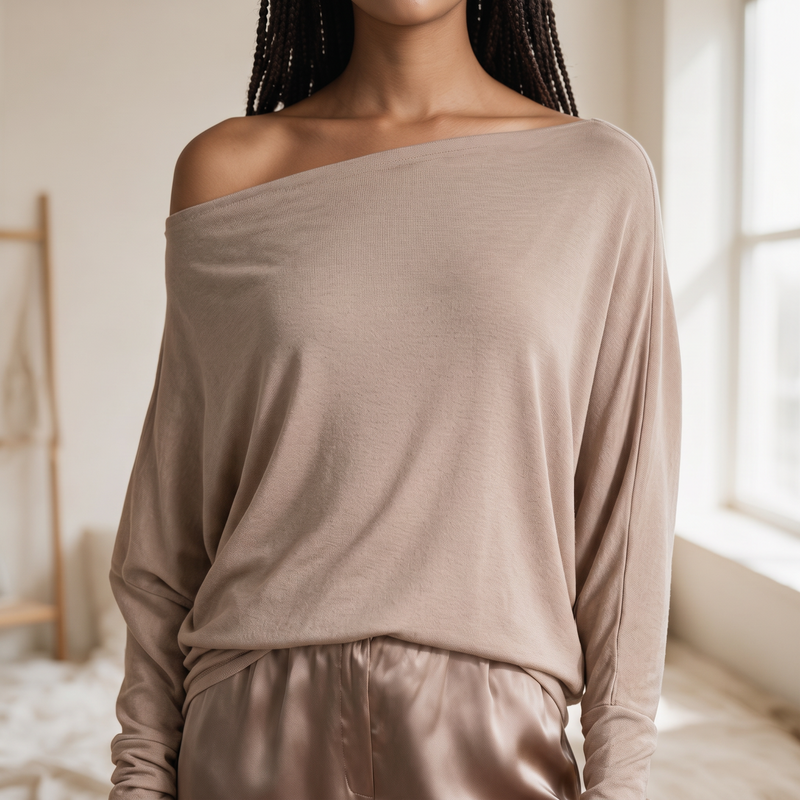 OKAKIE Maëlle draped hacci knit top in beige with a wide boat neckline worn off-shoulder and relaxed dolman sleeves.