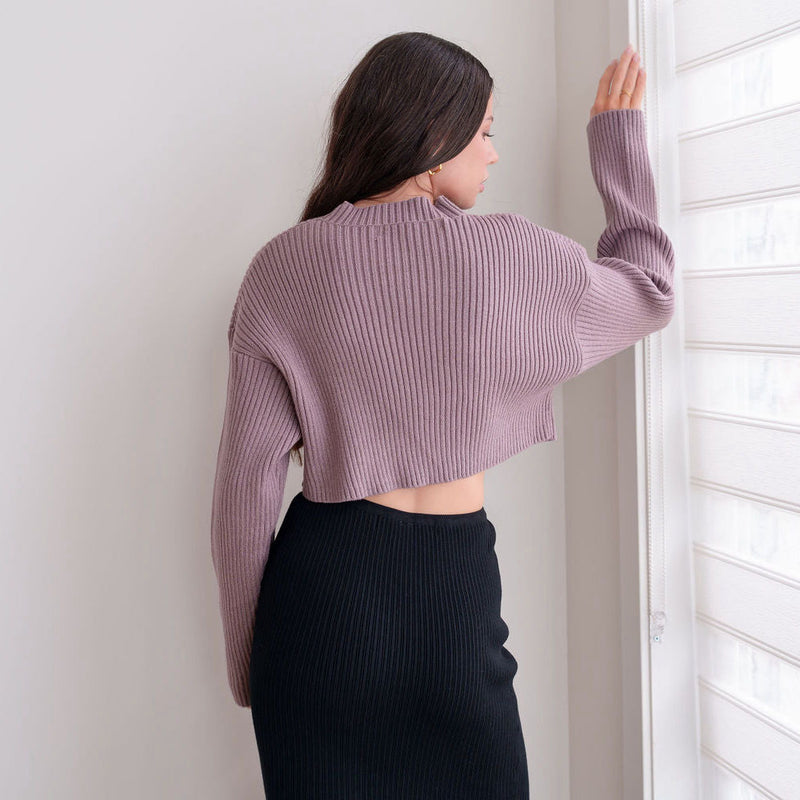 OKAKIE Elodie heavy mauve ribbed knit cropped sweater with drop shoulders worn by a woman standing by a window.