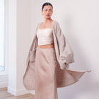 OKAKIE Étoile soft modal drape cardigan in beige worn over a satin camisole and skirt with a relaxed maxi silhouette.