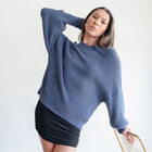 Model wearing an OKAKIE fuzzy blue mock-neck sweater with voluminous sleeves and a relaxed fit.