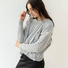 Model wearing OKAKIE grey heavyweight cotton cable knit sweater with intricate textures and oversized fit
