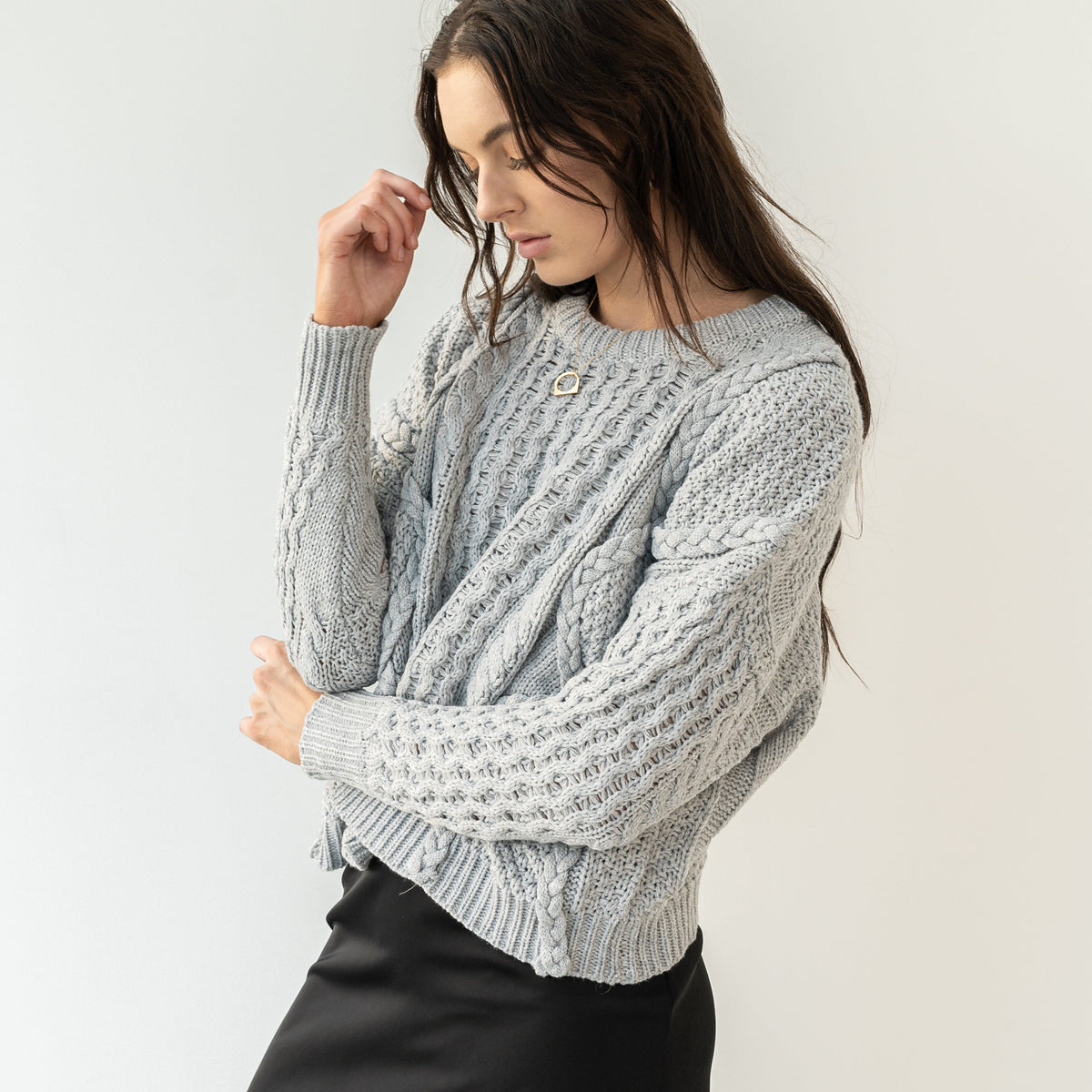 Model wearing OKAKIE grey heavyweight cotton cable knit sweater with intricate textures and oversized fit