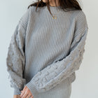 OKAKIE grey crew neck sweater with ribbed body and textured popcorn knit sleeves on a model
