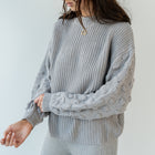 OKAKIE grey popcorn sleeve knit sweater with a ribbed crew neck and relaxed drop shoulders on a model